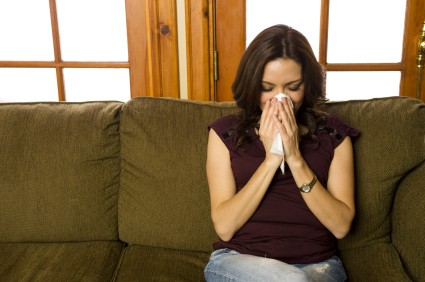 Woman blowing her nose in her home